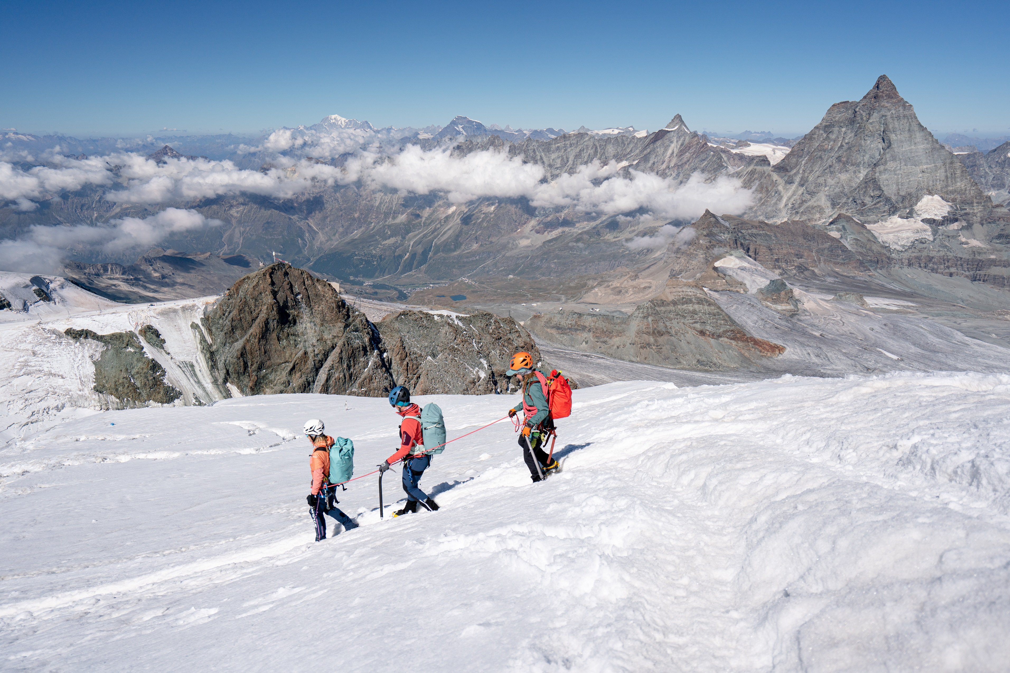 3 mountaineers hike down with the Matterhorn in the background