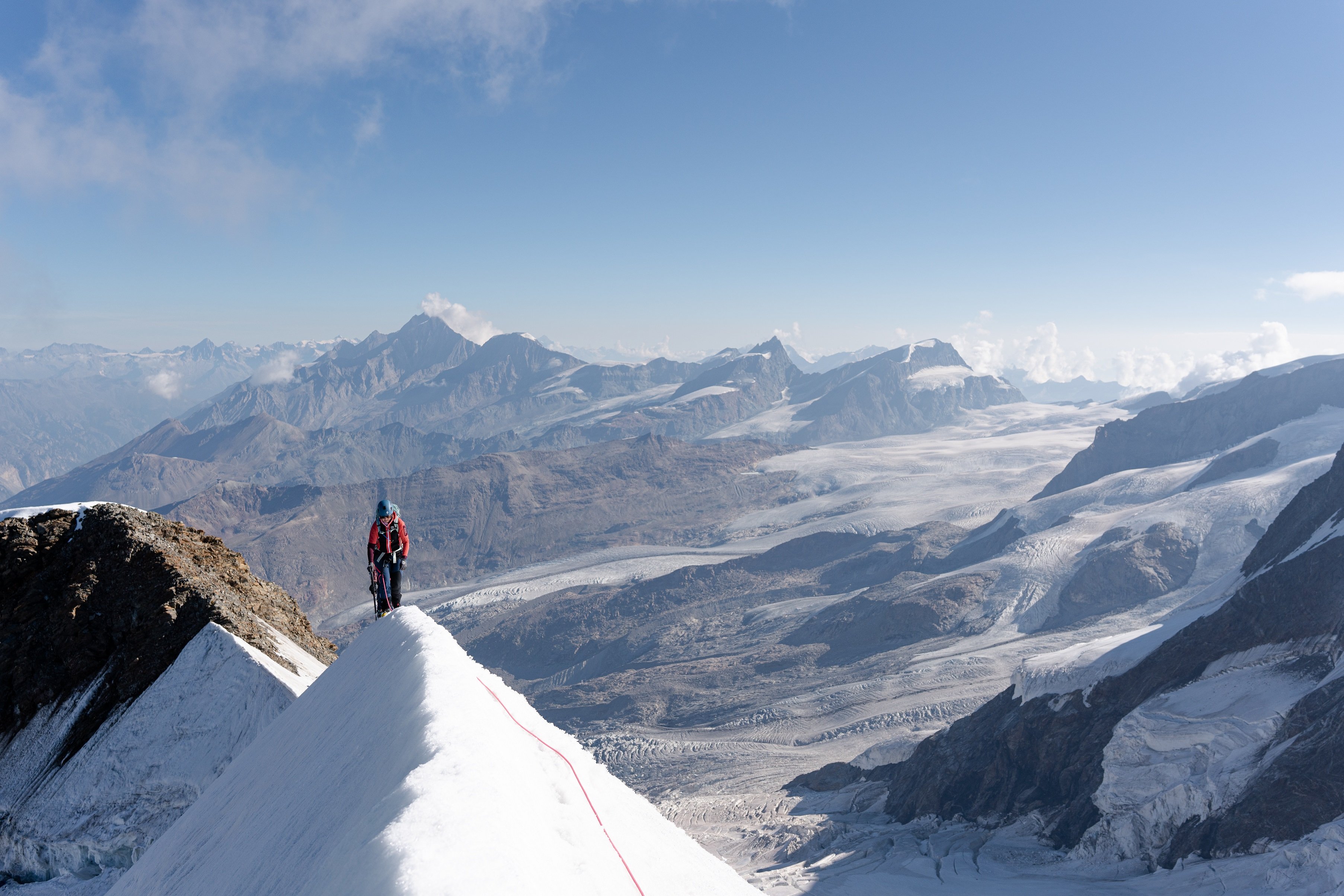 A single mountaineer walking along the knife edge of Castor