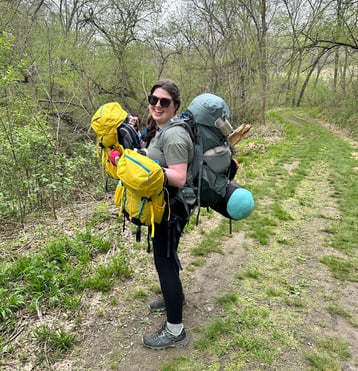 Author Amy Eastin holding both her girls backpacks while also wearing hers